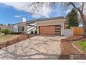 Single-story home showcasing its modern wood garage door, white siding, and manicured landscaping at 7102 S Harrison Ct, Centennial, CO 80122