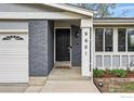 A welcoming front entrance featuring a black door, brick accents, and manicured landscaping at 9601 Sierra Dr, Arvada, CO 80005