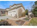 Exterior view showcasing the home's three-car garage and landscaped side yard with garden boxes at 11676 Montgomery Cir, Longmont, CO 80504