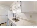 Bright kitchen featuring a stainless steel sink, quartz countertop, and a white refrigerator at 1225 Centaur Cir # A, Lafayette, CO 80026