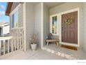 Inviting front porch with a decorative wreath, a cozy bench, and stone accents on the home's facade at 1453 Woodcock St, Berthoud, CO 80513