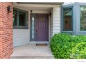Close up of front door with wreath, sidelight, sidelight and covered porch with manicured shrubbery at 1523 Lodge Ln, Boulder, CO 80303