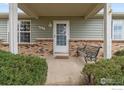 Inviting front porch with a charming bench, decorative brickwork, and freshly painted siding at 18030 E Loyola Dr, Aurora, CO 80013