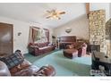 Cozy living room with a stone fireplace, ceiling fan, and abundant natural light from the windows at 18030 E Loyola Dr, Aurora, CO 80013