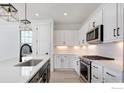 Modern kitchen with white cabinets, stainless steel appliances, and quartz countertops at 193 Liberty St, Erie, CO 80516
