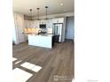Bright, open-concept kitchen boasts stainless appliances, an island, and wood grain flooring at 193 Liberty St, Erie, CO 80516