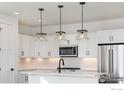 Bright kitchen with white cabinets, island, stainless steel appliances, and modern pendant lighting at 193 Liberty St, Erie, CO 80516