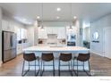 Modern kitchen featuring stainless steel appliances, white cabinets, a large island, and bar stool seating at 21574 E 59Th Dr, Aurora, CO 80019