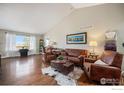 Spacious living room with hardwood floors, large windows, and comfortable leather seating at 2190 Coyote Creek Dr, Fort Lupton, CO 80621