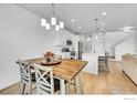 Open concept dining area features a wood table, modern light fixtures and is adjacent to the kitchen at 4027 E 98Th Pl, Thornton, CO 80229