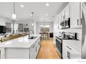 Bright kitchen featuring stainless steel appliances, white cabinets, and an island with a sink at 4027 E 98Th Pl, Thornton, CO 80229