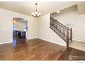 Spacious living room featuring hardwood floors and an elegant chandelier, leading to the staircase and arched entryway at 6709 2Nd St, Frederick, CO 80530