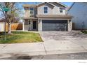 Charming two-story home with a gray exterior, attached garage, and a well-maintained lawn and landscaping at 10703 Butte Dr, Longmont, CO 80504