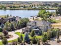 Gorgeous aerial view of estate home near lake and nestled within mature trees and landscaping at 12648 Waterside Ln, Longmont, CO 80504