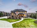 Stunning two-story home showcasing a lush green lawn, gray siding, stone detail, and an inviting entryway with picturesque surroundings at 12648 Waterside Ln, Longmont, CO 80504