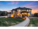 Stunning two-story home with manicured lawn and inviting entryway with stone and neutral-colored siding at 12648 Waterside Ln, Longmont, CO 80504