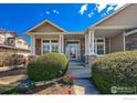 Charming home with a covered porch, landscaped front yard, and stone detailing at 1568 Stardance Cir, Longmont, CO 80504