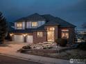 Charming two-story brick home with a three-car garage and beautifully landscaped front yard at twilight at 16261 W Ellsworth Ave, Golden, CO 80401
