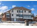 Back of home featuring large windows and a deck with partially snow-covered ground at 16261 W Ellsworth Ave, Golden, CO 80401