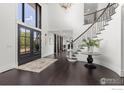 Grand foyer with dark wood floors, staircase, chandelier, and double front doors at 5800 Saint Vrain Rd, Longmont, CO 80503