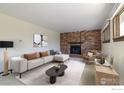Cozy living room featuring brick fireplace, neutral-toned furniture and natural light at 6844 Roaring Fork Trl, Boulder, CO 80301