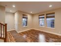 Bright living room featuring hardwood floors, three large windows, and neutral decor for a cozy feel at 8482 Parkland St, Broomfield, CO 80021