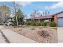 View of the front of the house with trees, gravel yard and driveway at 10249 W Grand Ave, Littleton, CO 80127
