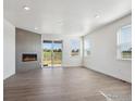 Open-concept living room with fireplace, wood floors, and sliding glass doors to the yard at 1102 Ridgefield Dr, Berthoud, CO 80513