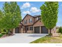 Charming home with a three-car garage, stone accents, a well-manicured lawn, and mature trees at 14958 Wistera Way, Broomfield, CO 80023