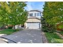 View of the home's exterior and driveway showcasing mature trees and landscaping at 2279 Apple Tree Pl, Erie, CO 80516