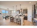 Stylish kitchen featuring a large center island with seating, modern pendant lights, and adjacent dining area at 2719 Crystal Springs Ln, Longmont, CO 80503