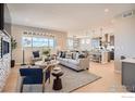 Inviting living room with stylish furniture, large windows, and an open layout to the modern kitchen and dining area at 2719 Crystal Springs Ln, Longmont, CO 80503