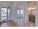 Open foyer with double glass doors, hardwood floors, and an entry to a half bathroom and sunny sitting room at 499 Muirfield Cir, Louisville, CO 80027