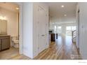 Bright hallway view with hardwood floors leading to an open living space and a convenient half bathroom at 499 Muirfield Cir, Louisville, CO 80027