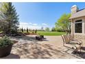 Stone patio with outdoor seating, a waterfall feature, and a lush green lawn with mature trees and mountain views at 5288 Waterstone Dr, Boulder, CO 80301