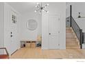 Modern entryway with light hardwood floors, updated lighting, and staircase with black railing at 586 Aztec Dr, Boulder, CO 80303
