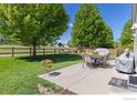 Serene backyard oasis with a concrete patio, lush green lawn, and mature trees, perfect for outdoor gatherings at 5912 Thistle Ridge Ave, Firestone, CO 80504