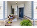 Inviting front porch seating area features neutral siding, a window and blue door at 5912 Thistle Ridge Ave, Firestone, CO 80504