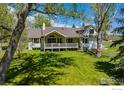 Spacious backyard with lush green grass, mature trees, and a charming back porch at 5986 Heather Way, Longmont, CO 80503