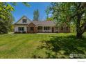 Lovely home with brick and white siding, a well-manicured lawn, and mature trees at 5986 Heather Way, Longmont, CO 80503