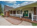Charming front porch with white railings, brick accents, and a vibrant green door at 5986 Heather Way, Longmont, CO 80503
