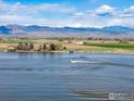 Breathtaking aerial shot of a lake with boats, rolling fields, and snow-capped mountains in the distance at 8138 Captains Ln, Longmont, CO 80504