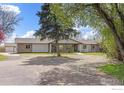 Charming ranch-style home with well-manicured front yard and mature trees on a sunny day at 8138 Captains Ln, Longmont, CO 80504