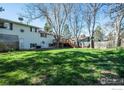 Spacious backyard featuring a green lawn, mature trees, and a wooden deck at 910 Sparta Dr, Lafayette, CO 80026