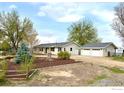 A ranch-style home with a detached garage and xeriscaping including native shrubbery and a blue spruce tree at 9752 Sierra Vista Rd, Longmont, CO 80504