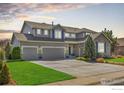 Spacious gray home boasts a well-manicured lawn, three-car garage, and complementary stone accents at 11722 Elmer Linn Dr, Longmont, CO 80504