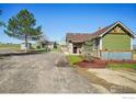 Beautiful home with green siding and gravel driveway with yard and blue sky at 205 S County Road 23, Berthoud, CO 80513