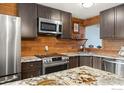 Well-equipped kitchen showcasing stainless steel appliances, granite countertops, and decorative wood backsplash at 2201 Pearl St # 321, Boulder, CO 80302