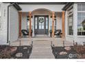 Inviting front porch with decorative door, columns, planters, and exterior lighting at 3796 Vale View Ln, Mead, CO 80542