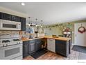 Well-lit kitchen featuring dark cabinetry, stainless steel appliances, wood countertops and updated flooring at 440 Fox St, Longmont, CO 80504